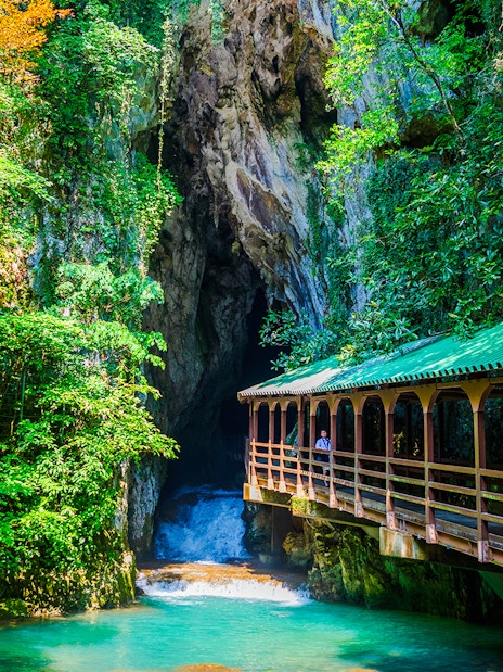 Entrance of a limestone cave with a wooden bridge, Plitvice Lakes National Park.