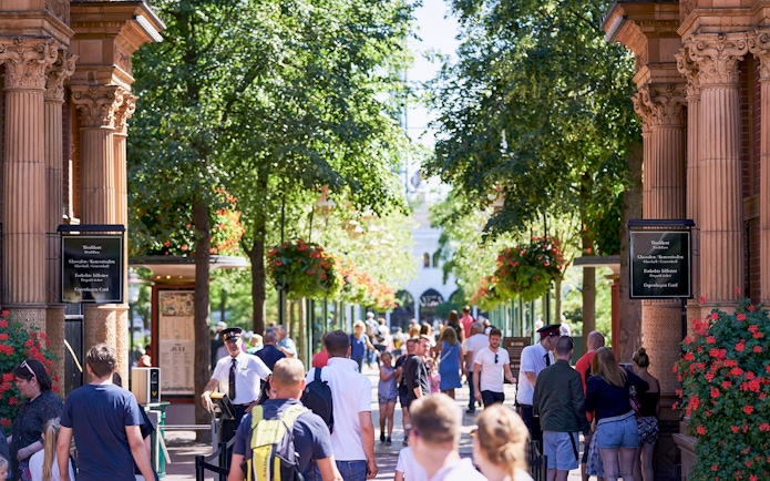 Visitors entering Tivoli Gardens in Copenhagen under ornate arches with lush greenery.