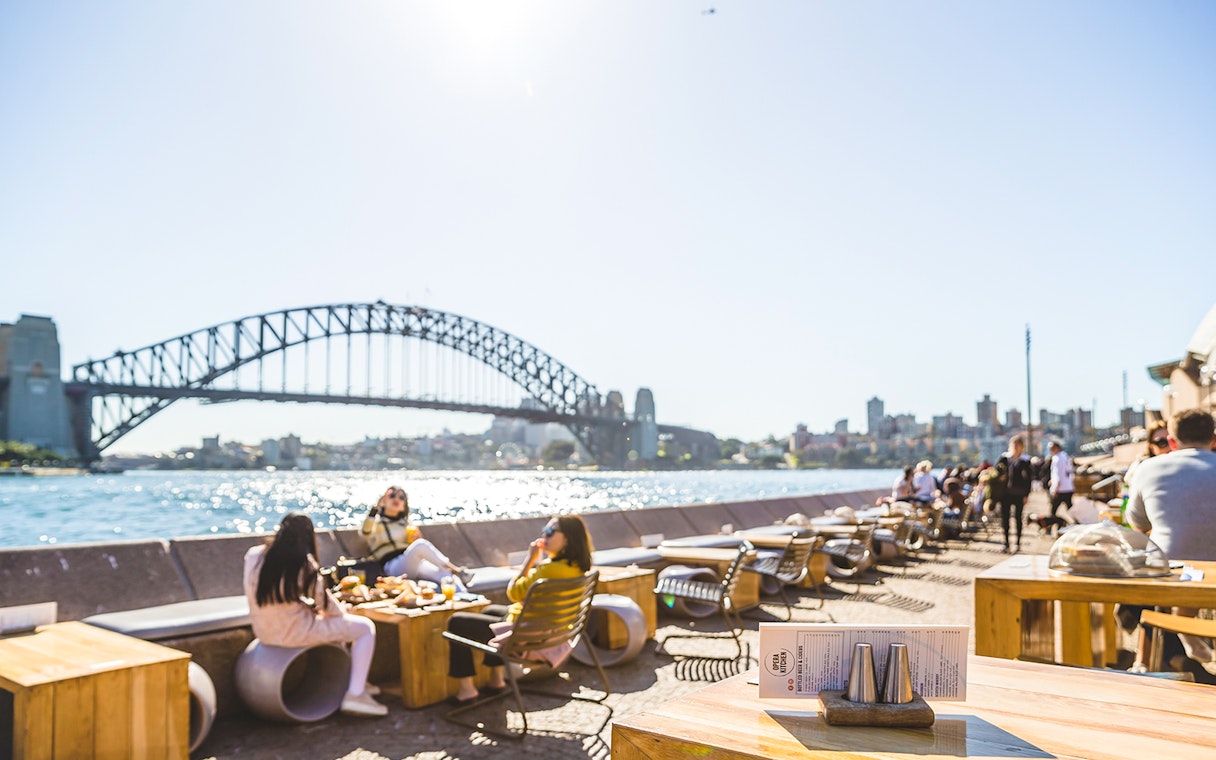 Sydney Opera House tour guests dining with view of Harbour Bridge.