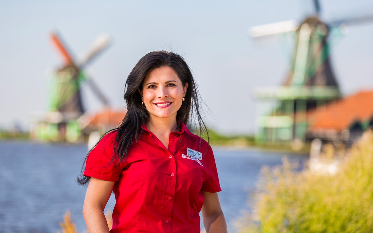 Tour guide in red shirt with windmills in Zaanse Schans, Holland.