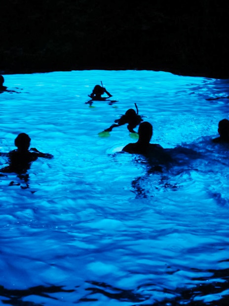 Snorkelers exploring the illuminated Blue Cave in Croatia.
