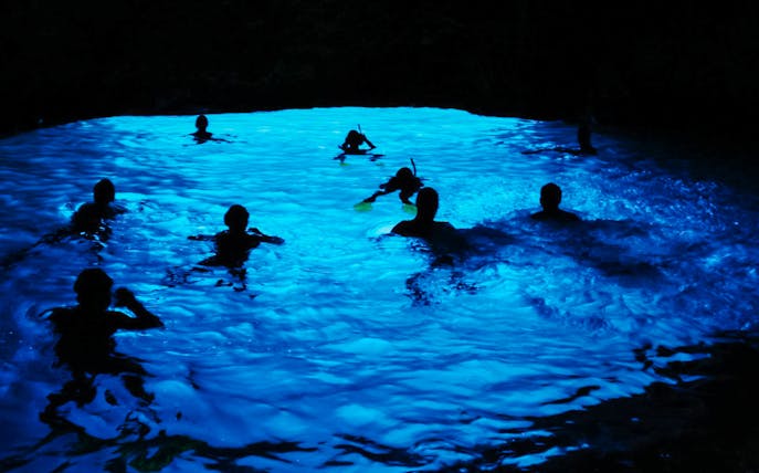 Snorkelers exploring the illuminated Blue Cave in Croatia.