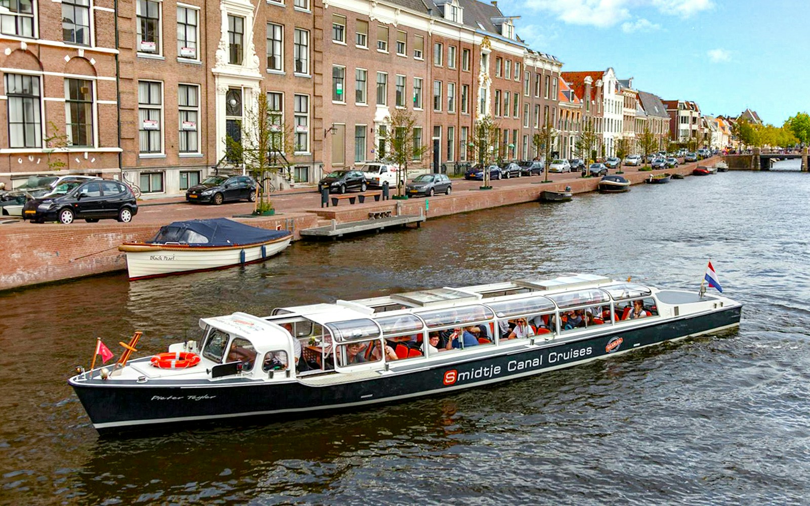 Canal cruise boat on Haarlem canal with passengers enjoying a cheese and wine tour.