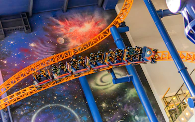 Roller coaster at Berjaya Times Square Theme Park with space-themed backdrop.