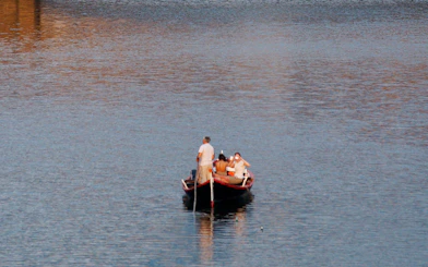 Guided boat tour on a Florentine gondola with tourists on a calm river.
