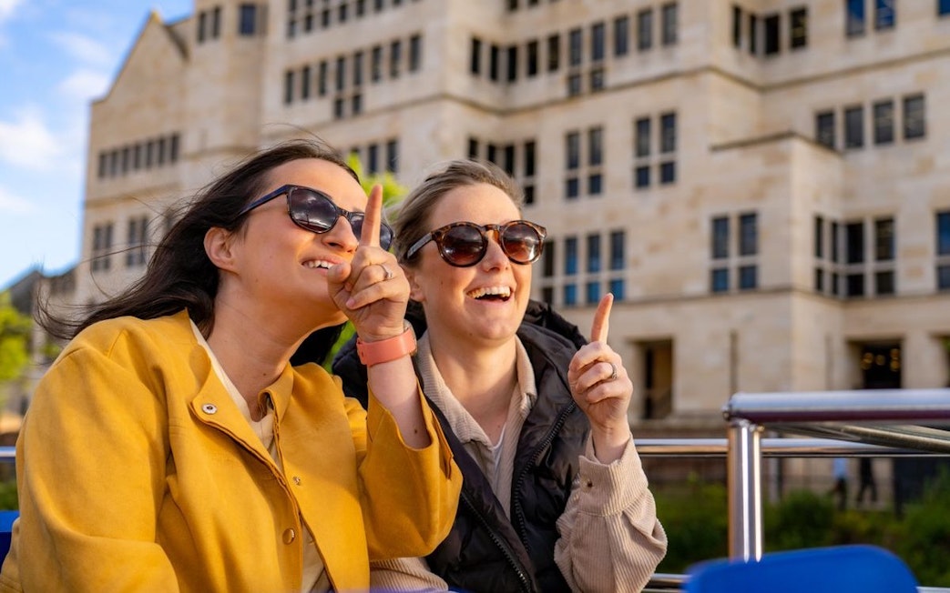 Two people enjoying a York sightseeing cruise, pointing at landmarks.