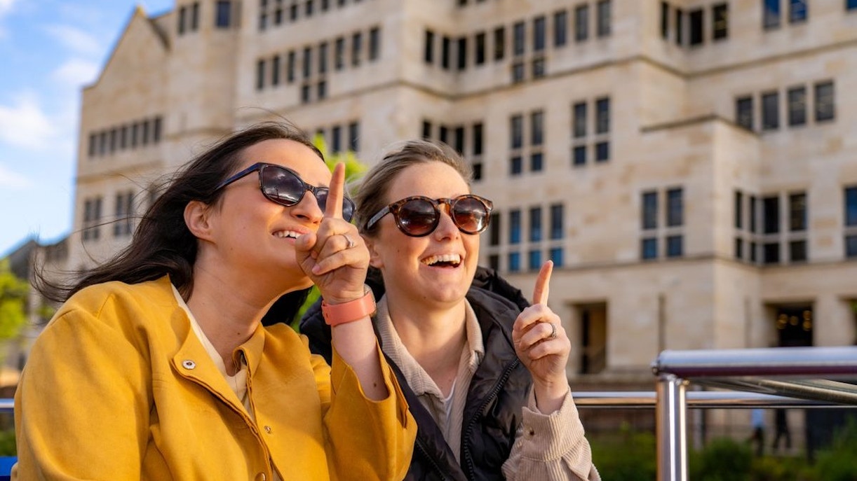 Two people enjoying a York sightseeing cruise, pointing at landmarks.