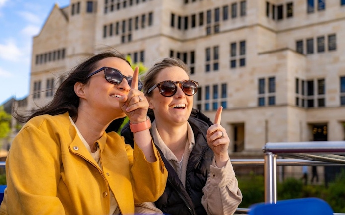 Two people enjoying a York sightseeing cruise, pointing at landmarks.
