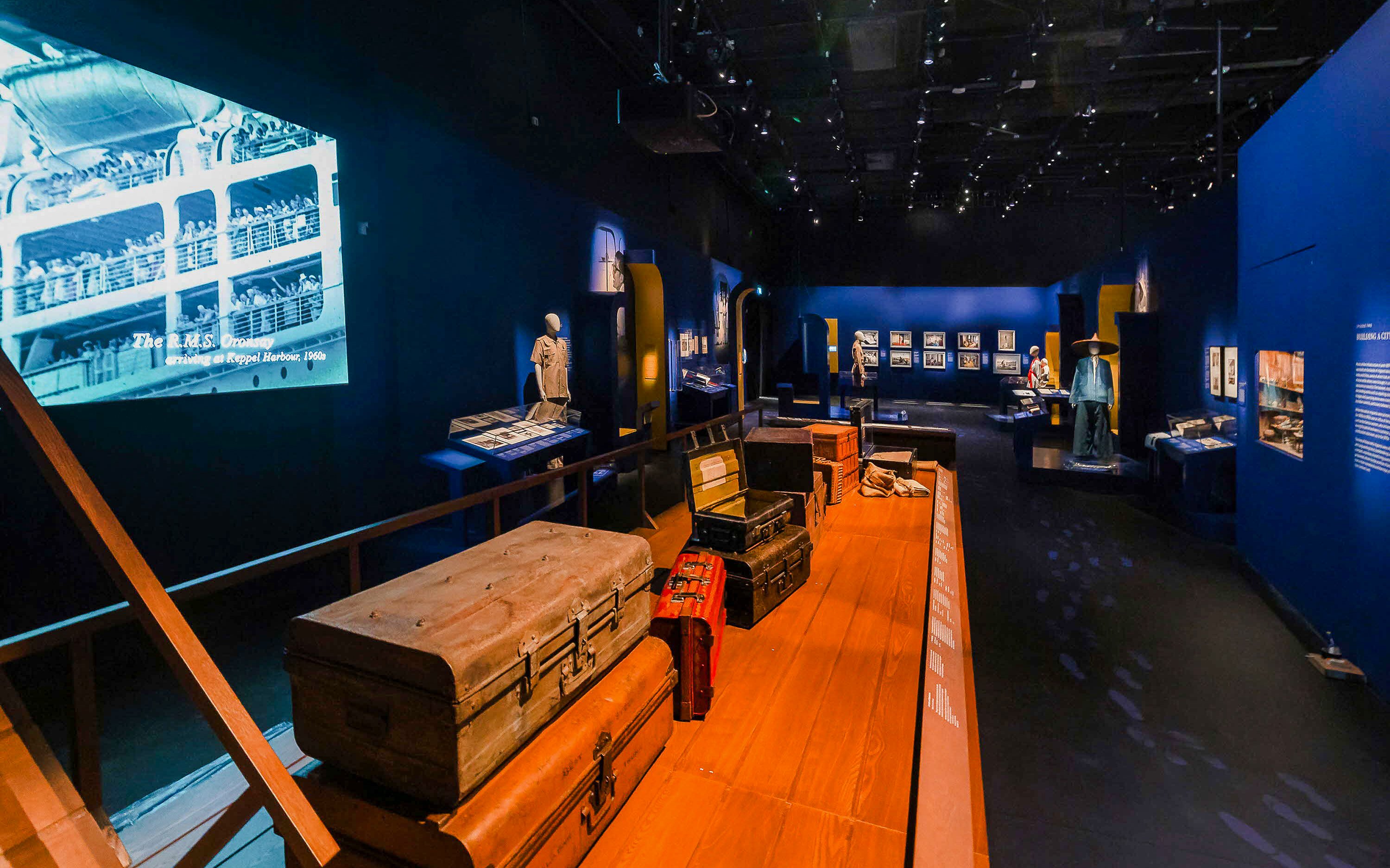 Exhibition room with vintage suitcases and historical displays at the National Museum of Singapore.