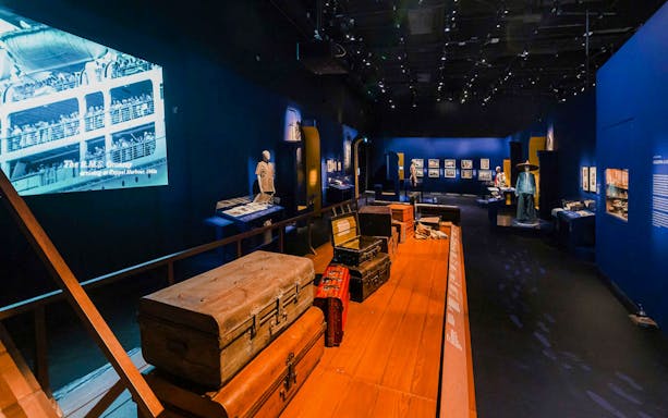 Exhibition room with vintage suitcases and historical displays at the National Museum of Singapore.