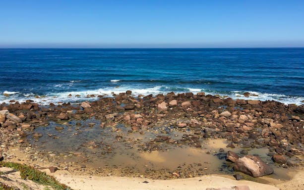 Rocky shoreline along the Tonnare Trail to Gonnesa, with waves crashing on the coast near Portoscuso.
