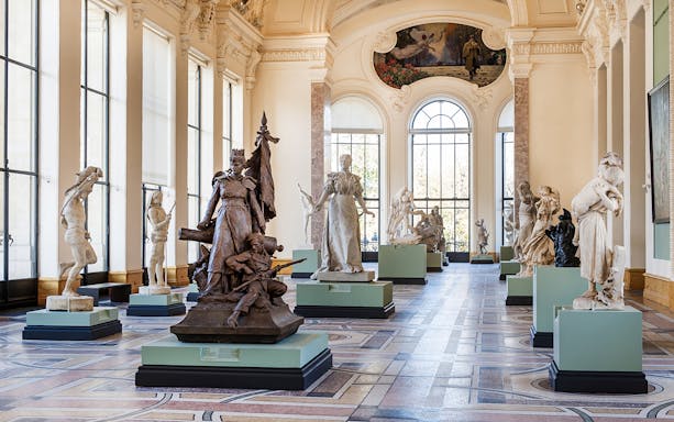 Sculpture gallery inside Petit Palais, Paris, featuring classical statues and ornate architecture.