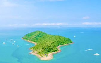 Aerial view of yachts near a lush island in Pattaya during a 3-island hopping cruise.