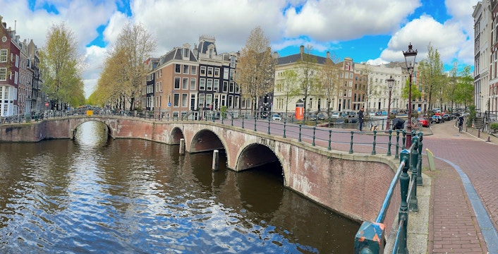 Amsterdam canal ring with arched bridge and historic buildings along the water.