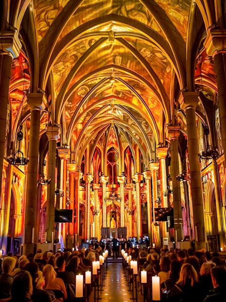 Audience watching LUMINISCENCE Manchester 360° Immersive Show in a cathedral with illuminated arches.