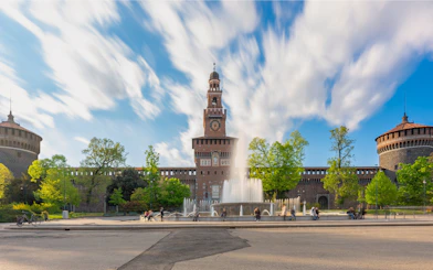 Sforza Castle in Milan with central tower and fountain in foreground.