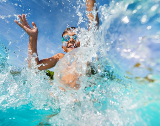 Young boy splashing in water at a water park.