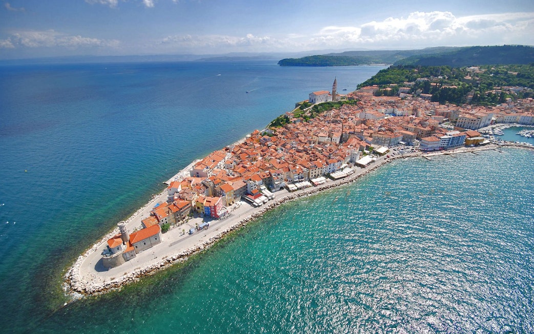 Aerial view of Piran Town, Slovenia, featuring coastal buildings and the Adriatic Sea.