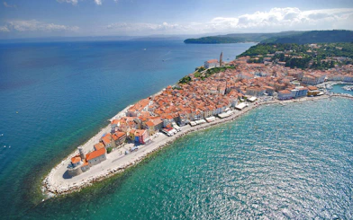 Aerial view of Piran Town, Slovenia, featuring coastal buildings and the Adriatic Sea.