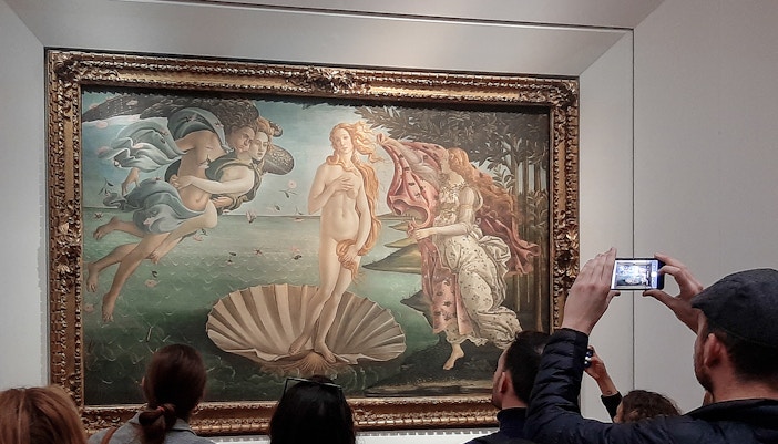 Tourists capturing the iconic 'Birth of Venus' by Sandro Botticelli at the Uffizi Gallery, immersed in the painting's historical grandeur