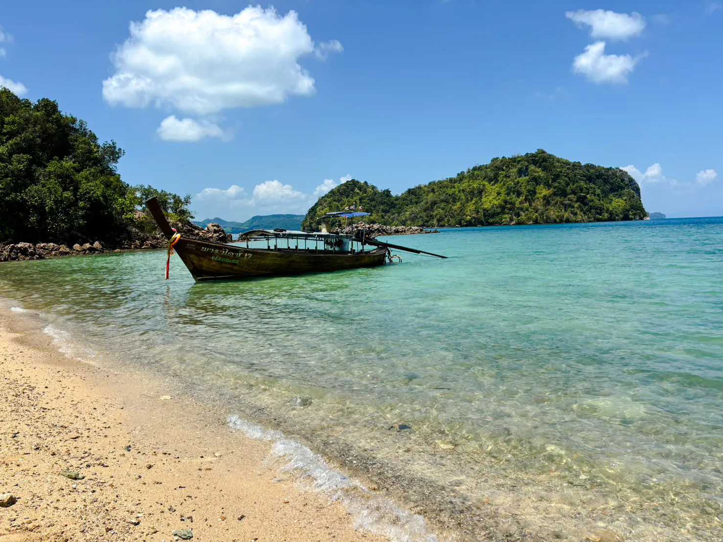 Longtail boat anchored near Hong Islands, Krabi, with clear water and lush greenery.