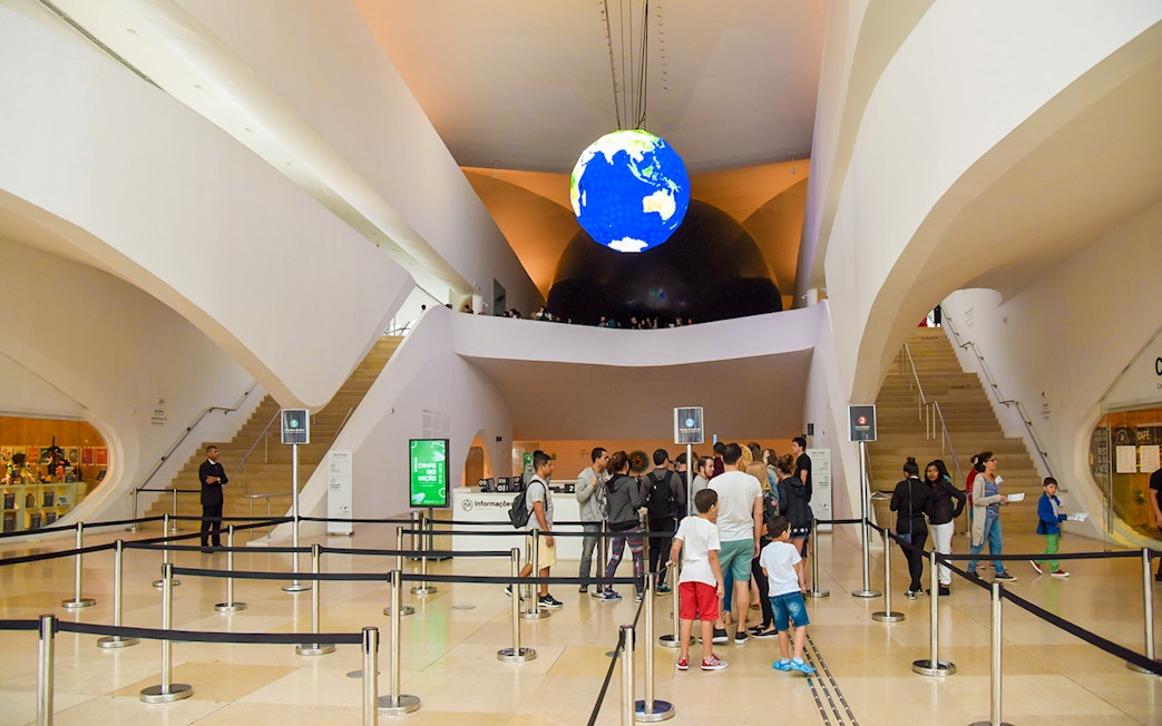 Tourists queue at the entrance of the Aquário Aquarium, featuring a globe display.