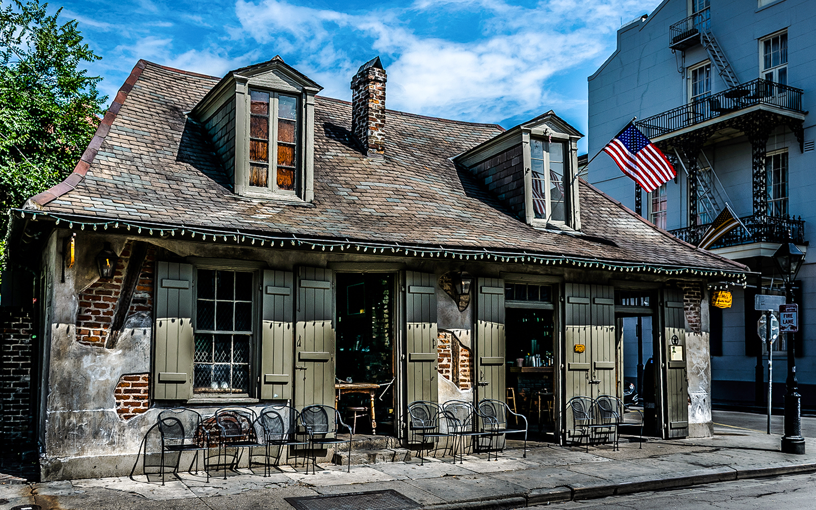 Historic Blacksmith Bar on Bourbon Street, New Orleans, with American flag and outdoor seating.
