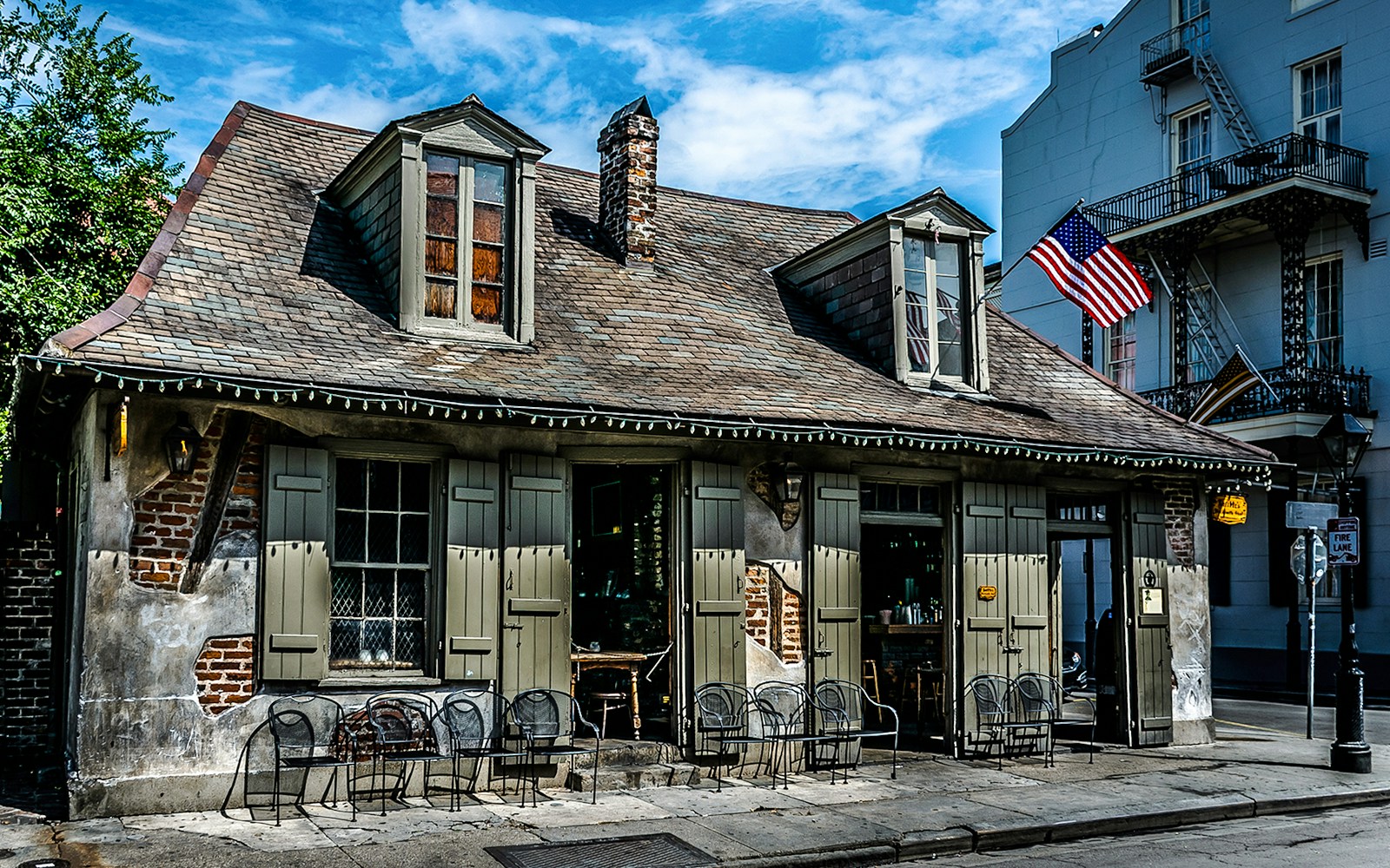 Historic Blacksmith Bar on Bourbon Street, New Orleans, with American flag and outdoor seating.