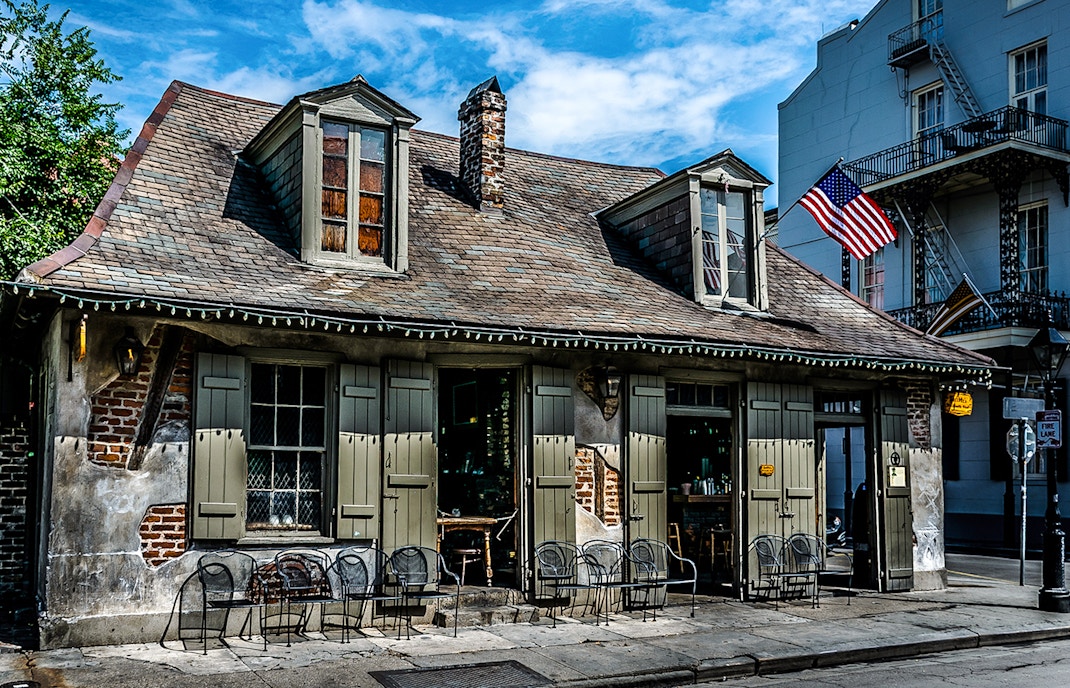 Historic Blacksmith Bar on Bourbon Street, New Orleans, with American flag and outdoor seating.