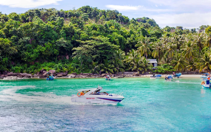 Speedboat on turquoise waters near lush island coast, Phu Quoc, Vietnam.