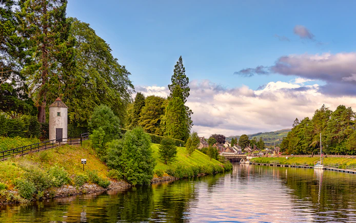 Caledonian Canal with lush greenery and a small tower near the water.