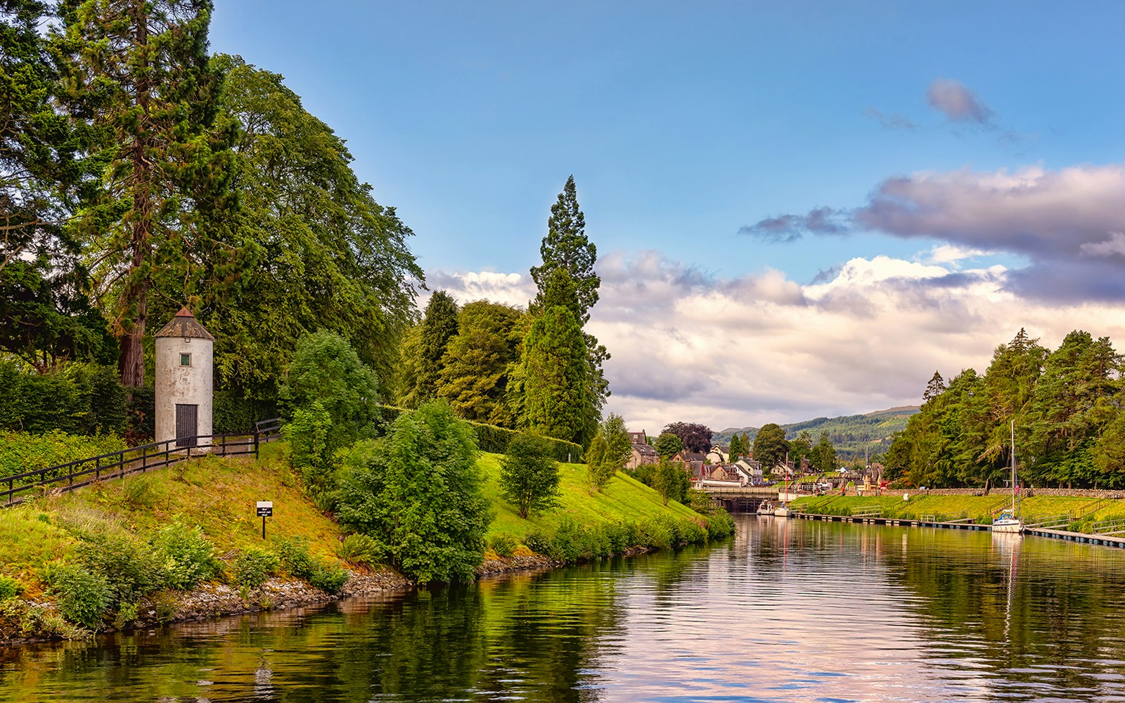 Caledonian Canal with lush greenery and a small tower near the water.