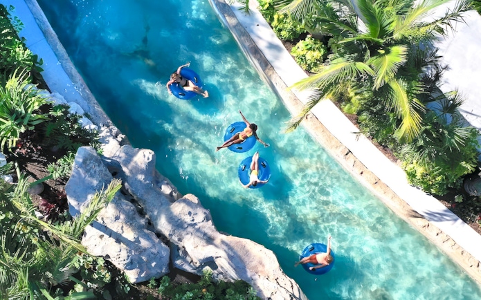 People floating on blue tubes in a lazy river at Baha Mar Waterpark, Nassau, Bahamas.