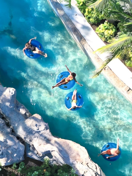 People floating on blue tubes in a lazy river at Baha Mar Waterpark, Nassau, Bahamas.