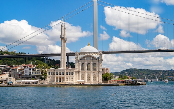 Ortaky Mosque with white stone architecture and twin minarets by the Bosphorus Bridge, Istanbul.
