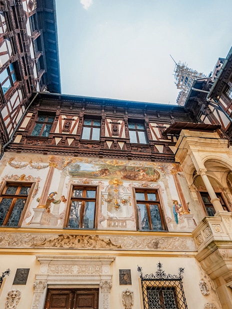 Inner courtyard walls of Peles Castle with detailed frescoes and ornate architecture.