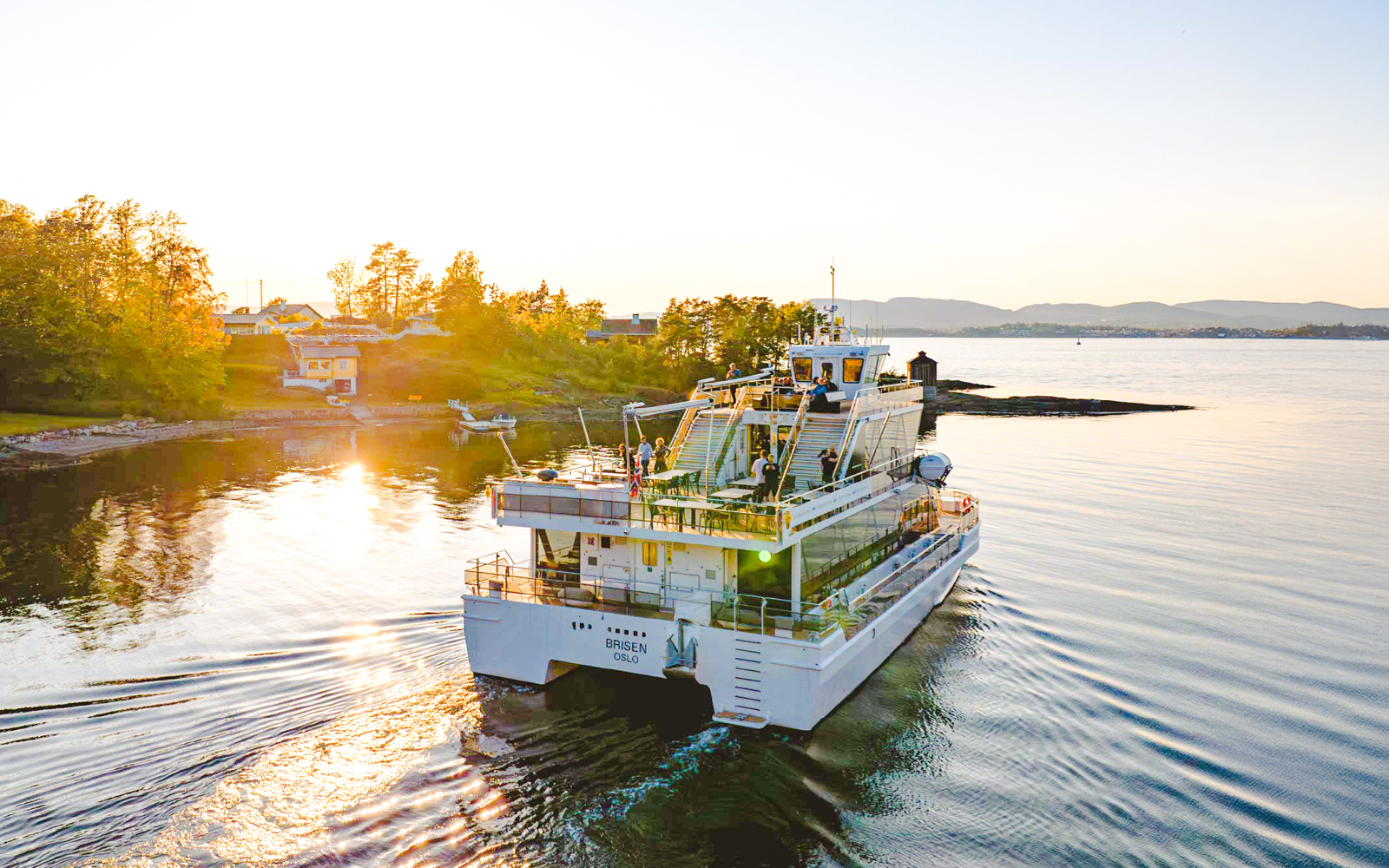 Silent fjord cruise boat near Oslo with passengers enjoying sunset views.