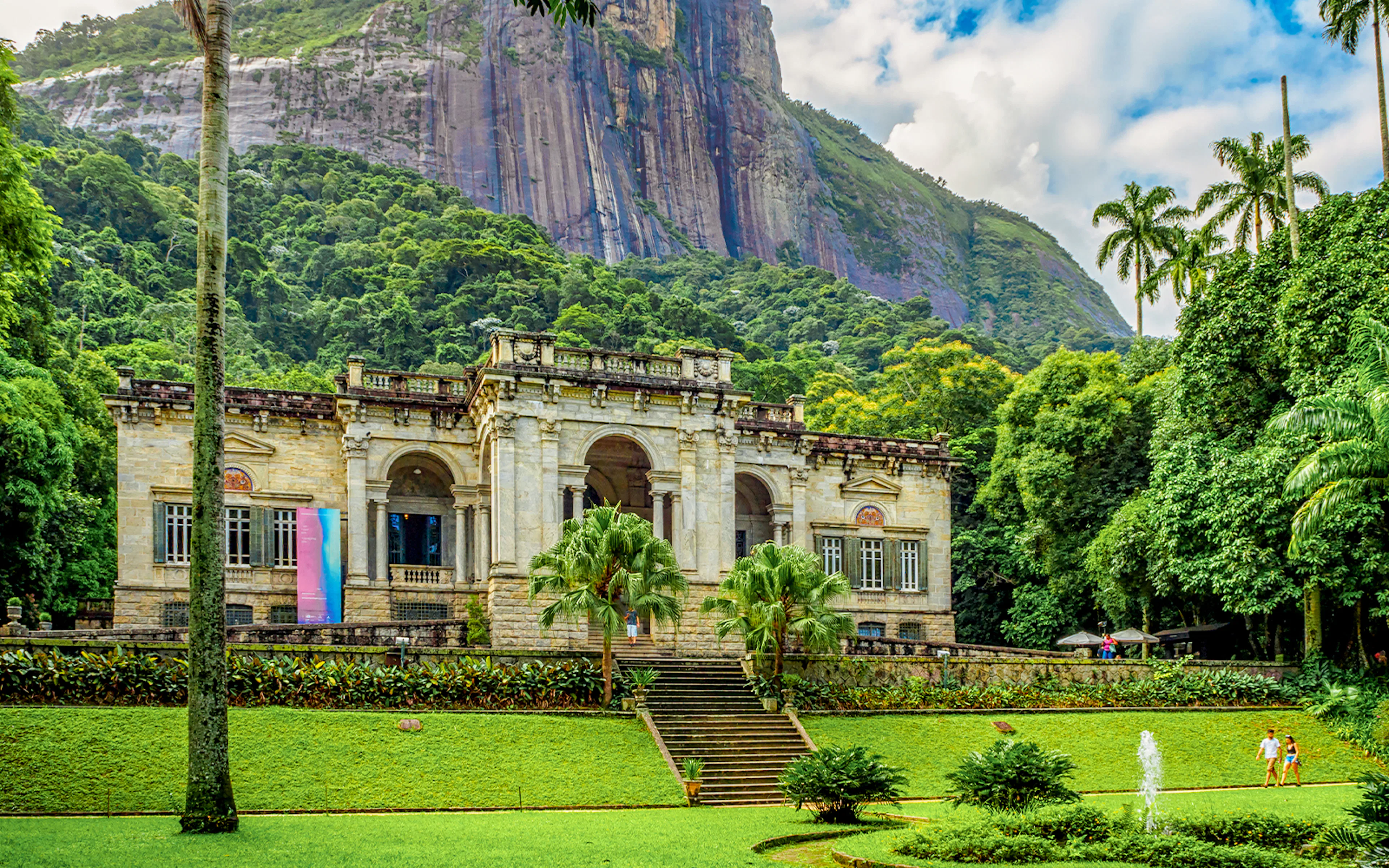 Historic mansion in Parque Lage, Rio de Janeiro, with lush gardens and mountain backdrop.