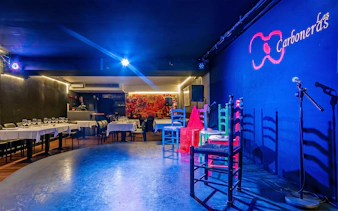 Tablao LAS CARBONERAS stage set for Flamenco show with colorful chairs and microphone.