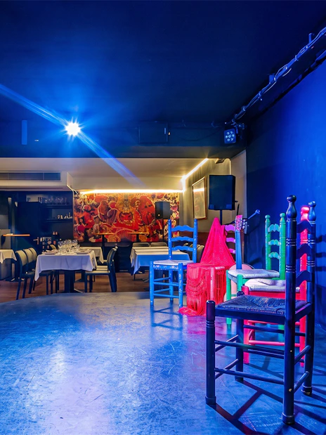 Tablao LAS CARBONERAS stage set for Flamenco show with colorful chairs and microphone.