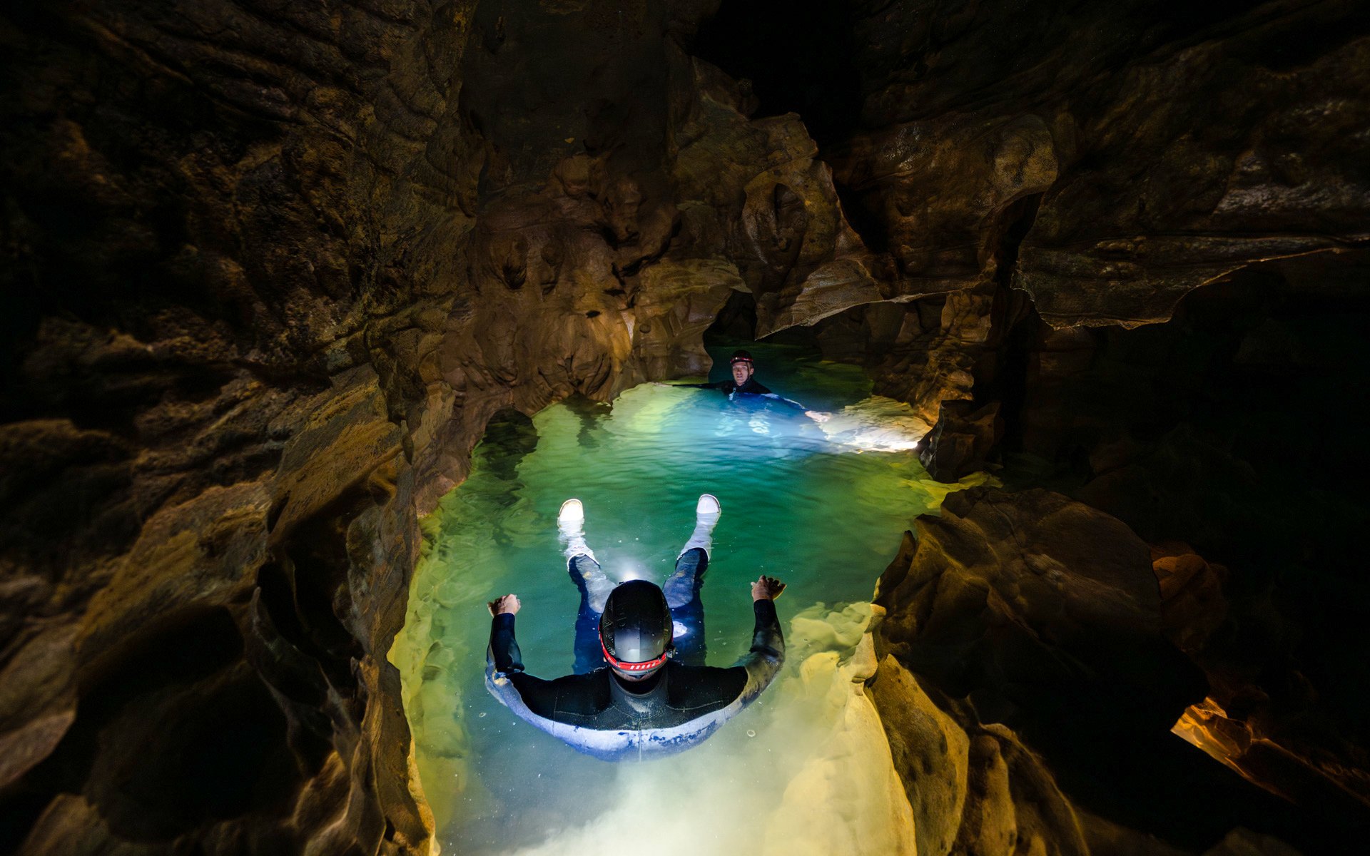 Visitors floating in Okohua Glowworm Cave, illuminated by cave lights, during the Waitomo Experience tour.