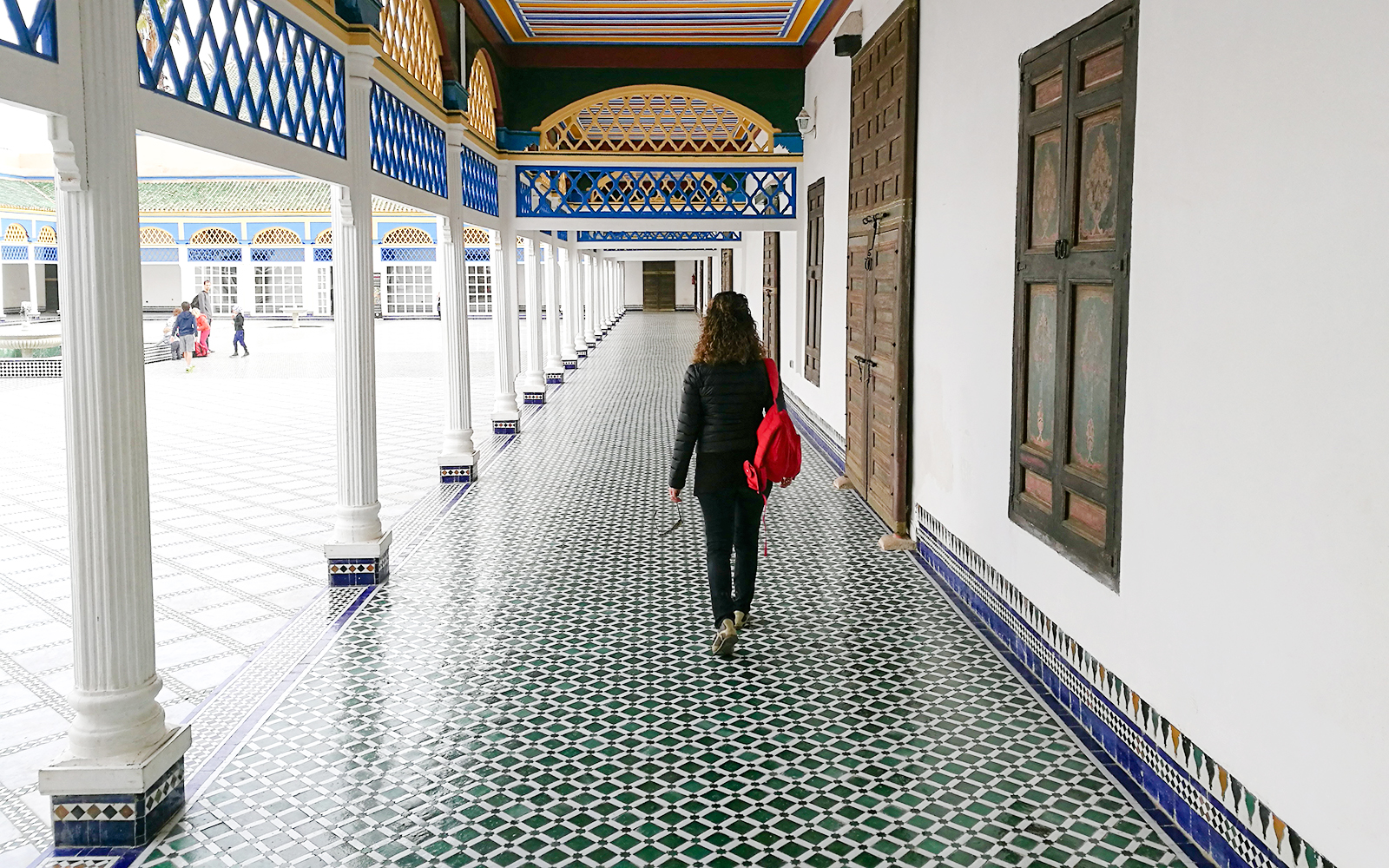 Tourist walking through tiled corridor in Bahia Palace, Marrakech, Morocco.