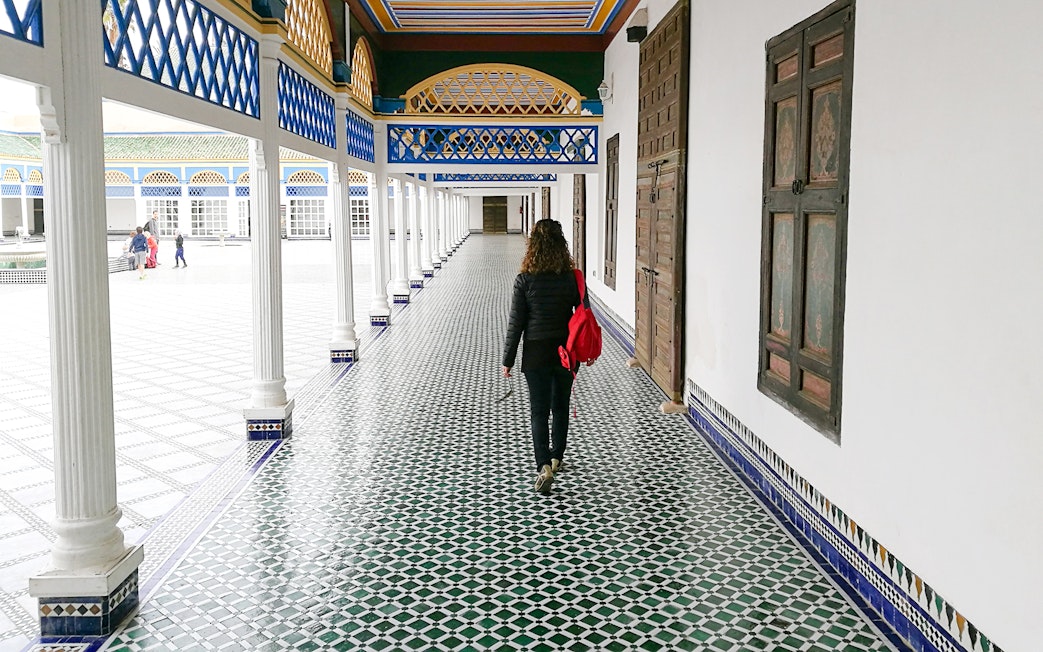 Tourist walking through tiled corridor in Bahia Palace, Marrakech, Morocco.