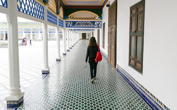 Tourist walking through tiled corridor in Bahia Palace, Marrakech, Morocco.