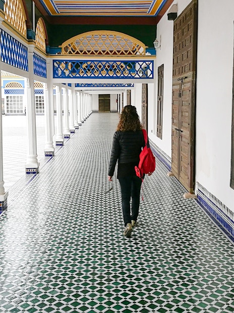 Tourist walking through tiled corridor in Bahia Palace, Marrakech, Morocco.