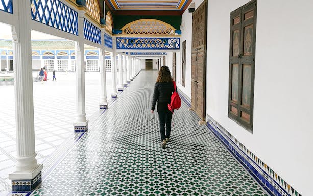 Tourist walking through tiled corridor in Bahia Palace, Marrakech, Morocco.
