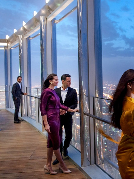 Tourists enjoying the view from the Burj Khalifa lounge in Dubai at night.