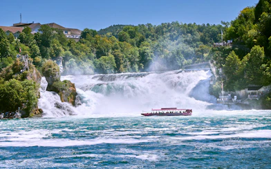 Boat with tourists approaching Rhine Falls in Switzerland.