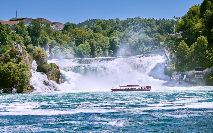 Boat with tourists approaching Rhine Falls in Switzerland.