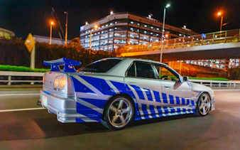 Car drifting on Tokyo street at night during Fast & Furious Tokyo Drift III Experience.